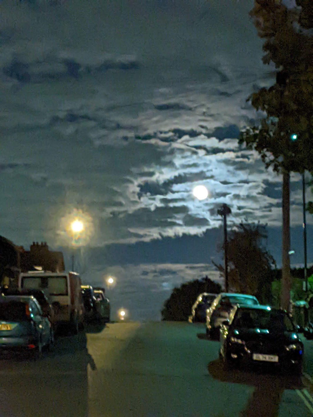 full moon at night, view from street with parked cars and street lights